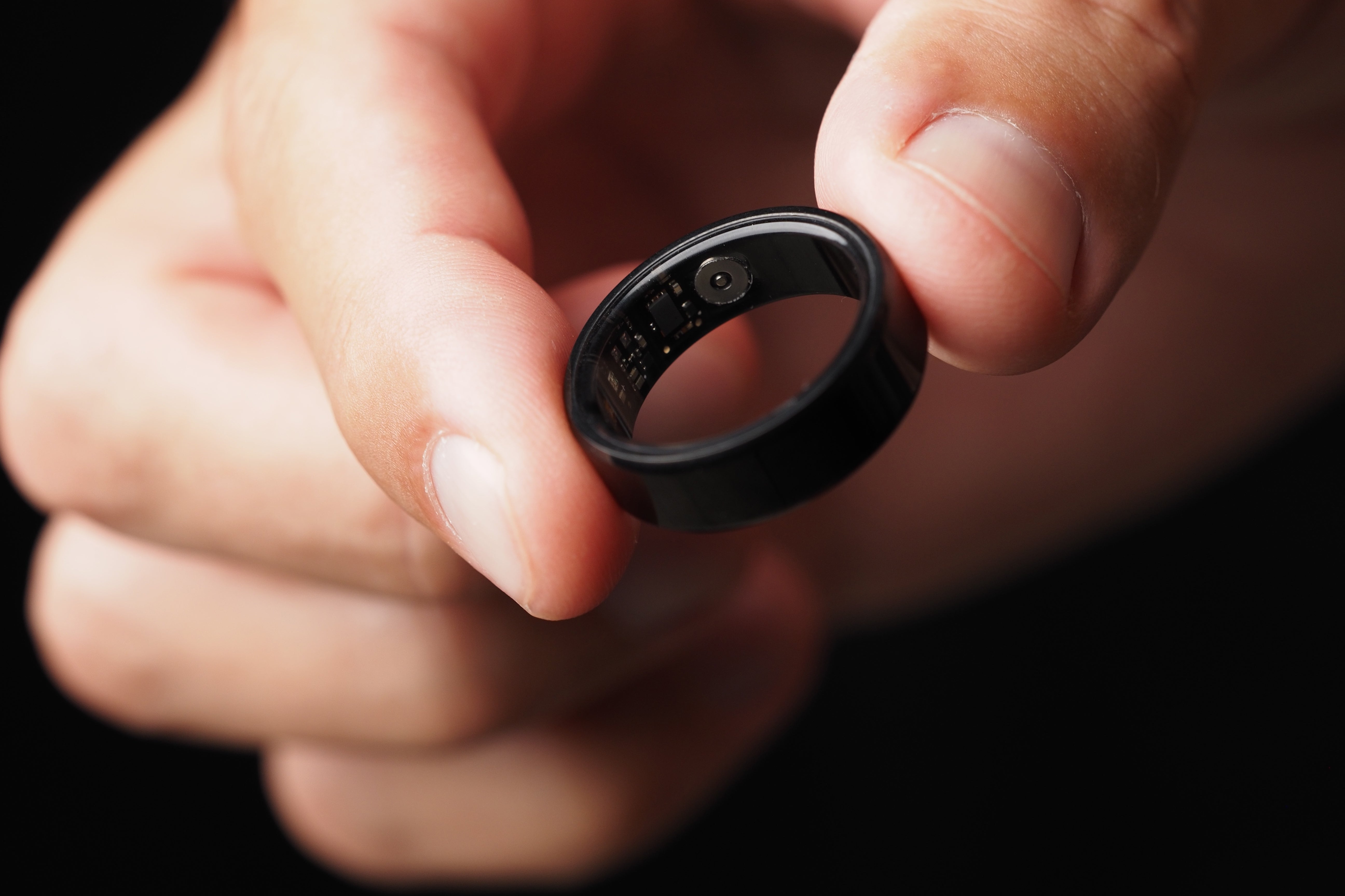 Close-up of a finger holding a smart ring between the fingertips