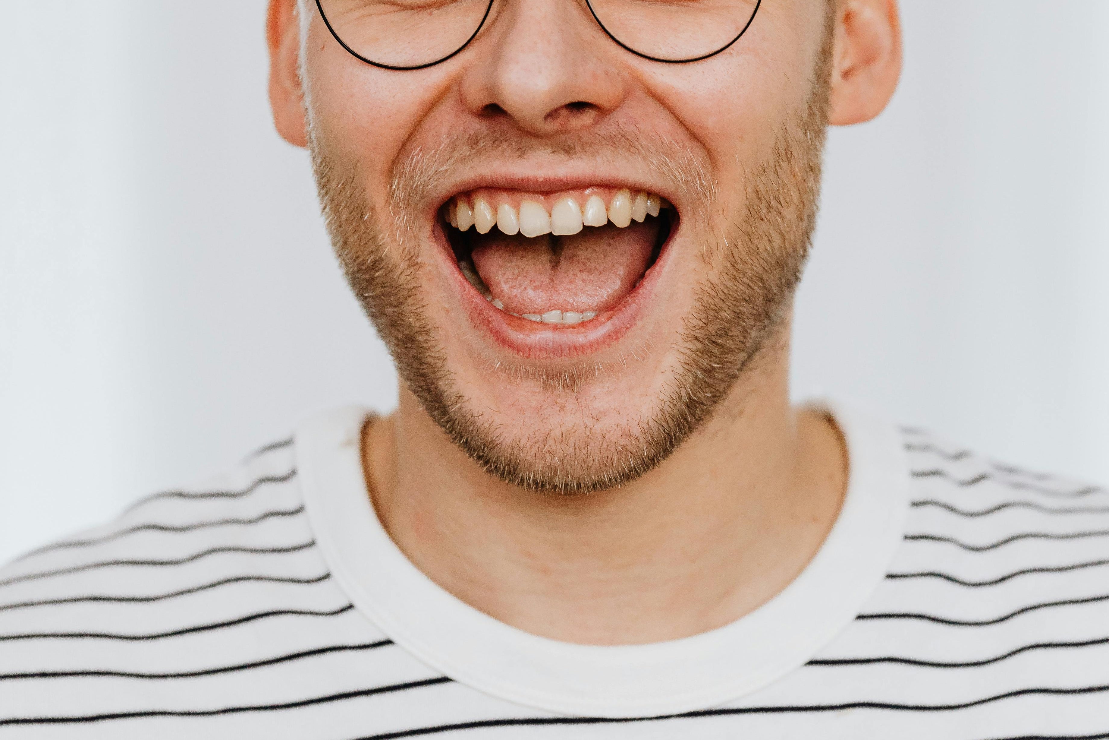 A man smiling broadly and showing his front teeth, demonstrating good oral health