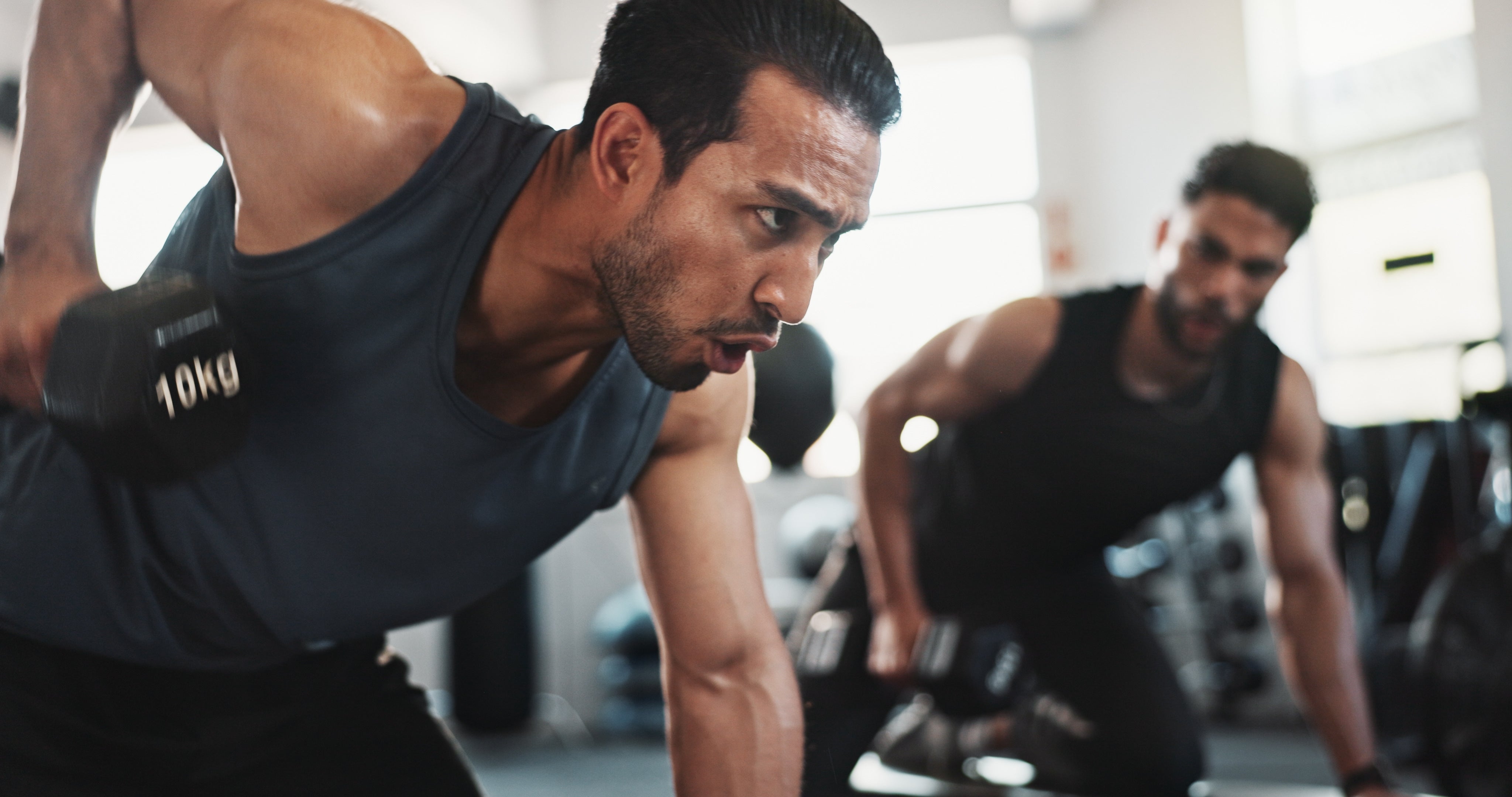 Man in gym lifting a dumbbell for shoulder exercise, demonstrating an active lifestyle