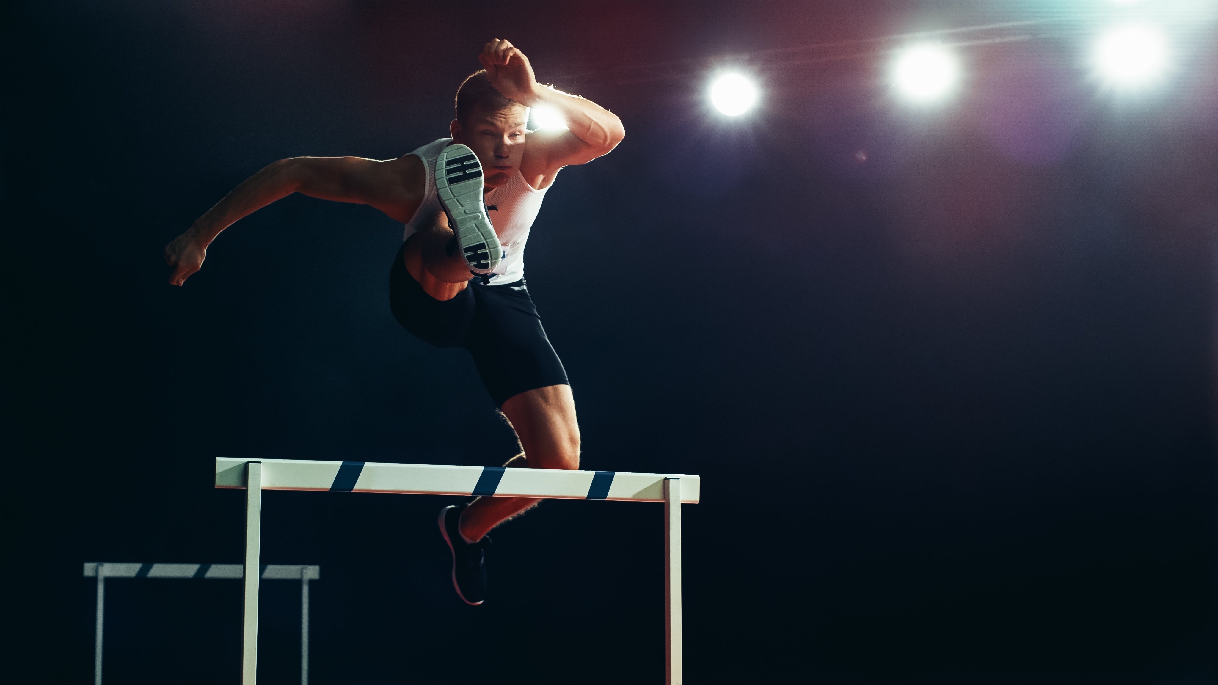 Athletic man jumping over a hurdle during a track and field event