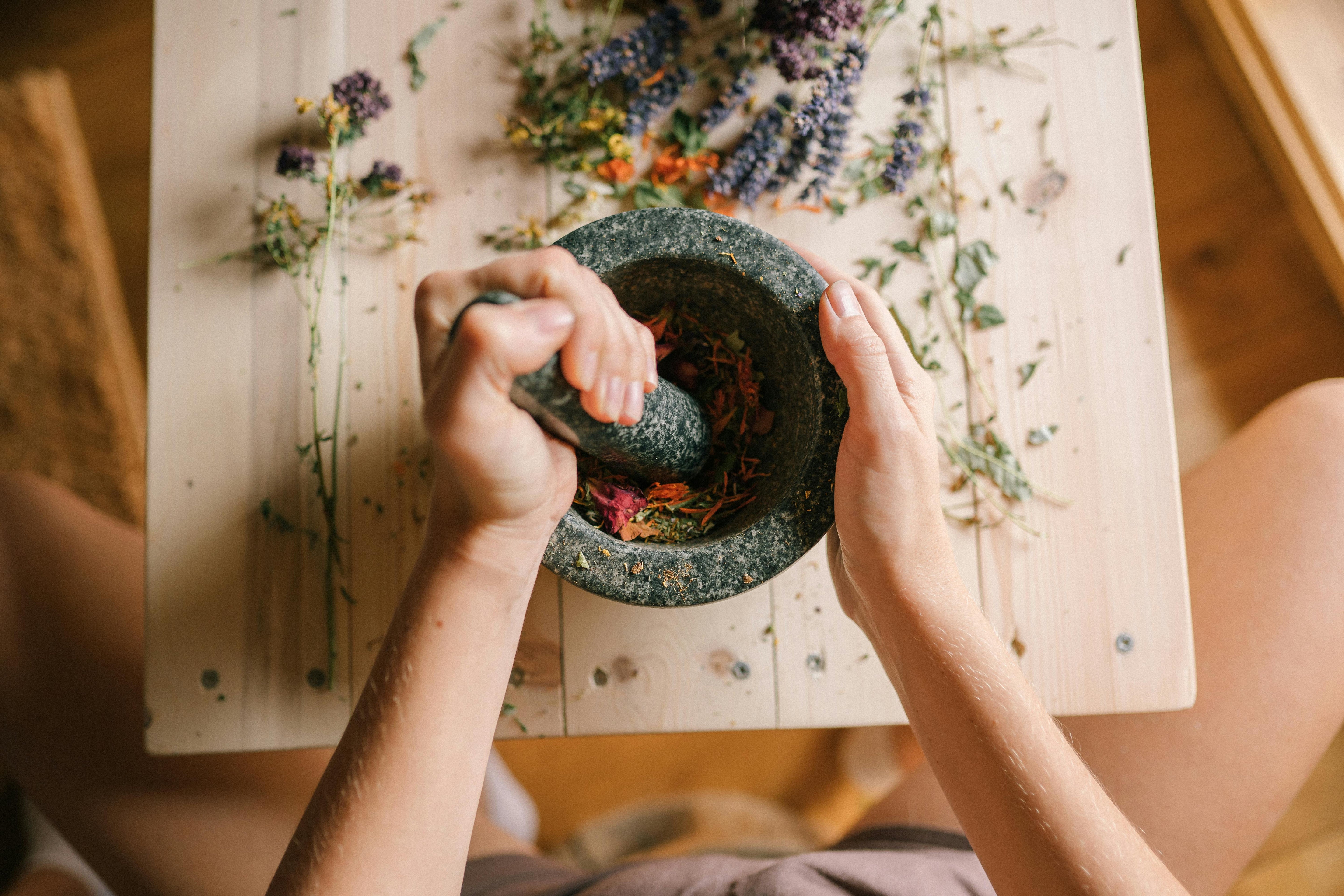 woman grinding herbs with stone pestle and mortar