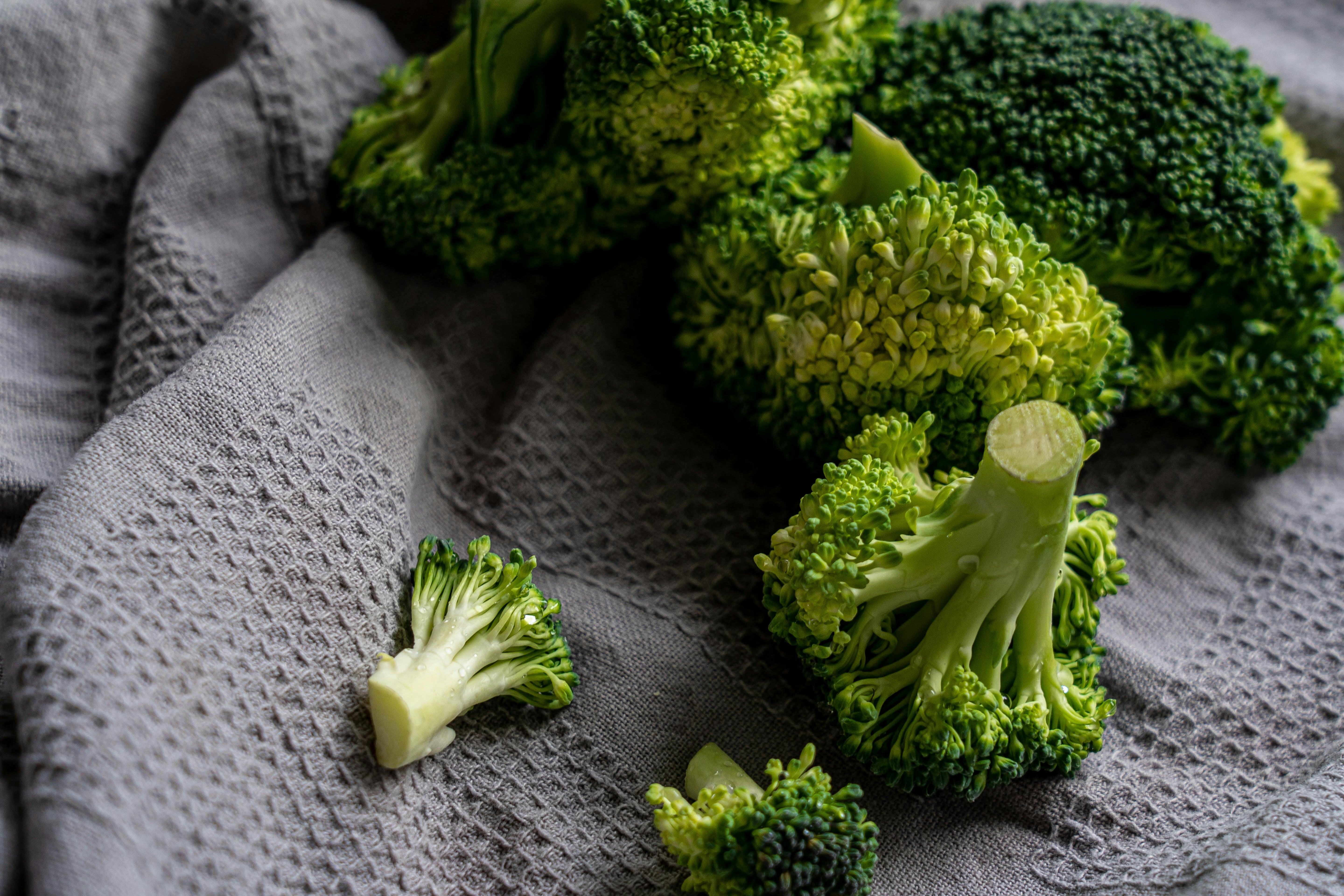 Image of broccoli and broccoli segments on top of a grey tea towel 