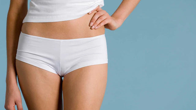 Close-up of a woman's lower body wearing white shorts, representing vaginal health